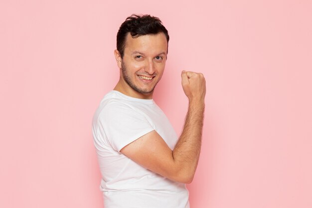 Um jovem do sexo masculino com uma camiseta branca posando e sorrindo