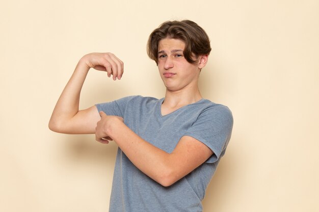 Um jovem do sexo masculino com uma camiseta cinza flexionando