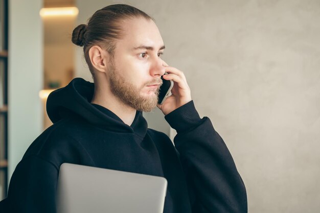 Foto grátis um jovem empresário com barba está falando em um smartphone