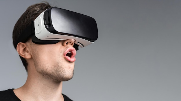 Um jovem está animado enquanto usa óculos VR fundo cinza