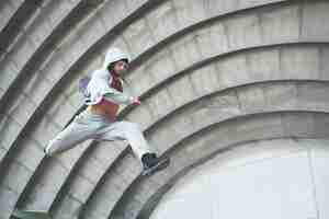 Foto grátis um jovem está pulando. parkour no espaço urbano, atividade esportiva.