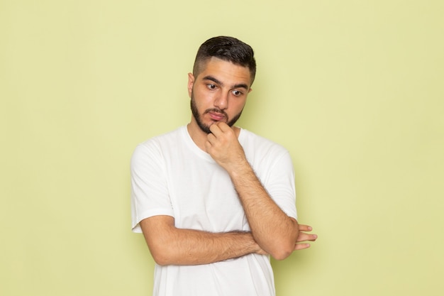 Um jovem homem de camiseta branca com uma visão frontal profundamente pensando