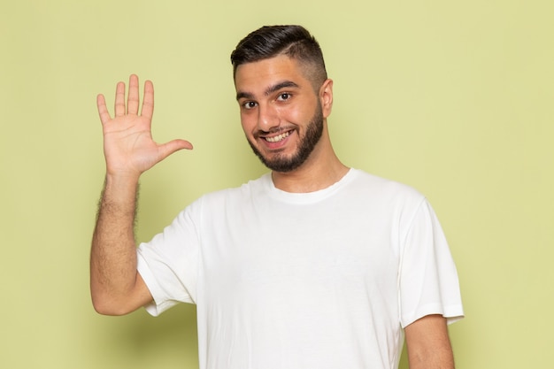 Um jovem homem de camiseta branca, de frente para o outro, cumprimenta e sorri