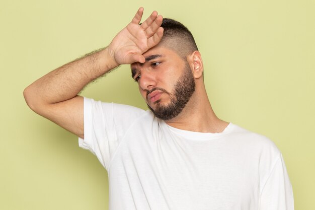 Um jovem homem de frente para uma camiseta branca com uma expressão cansada