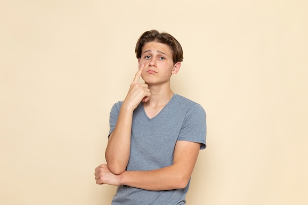 Um jovem homem de frente para uma camiseta cinza com uma expressão triste