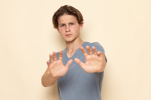 Um jovem homem de frente para uma camiseta cinza posando com cautela