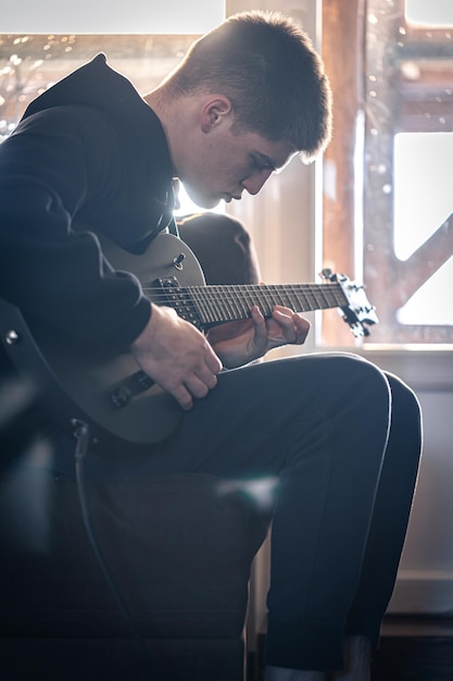 Um jovem toca guitarra elétrica em seu quarto