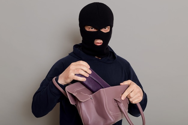 Um ladrão criminoso tira uma carteira de uma bolsa roubada