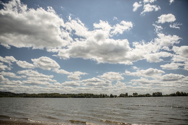 Um lago sob o céu nublado com uma floresta