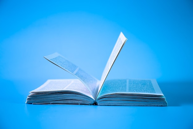 Um livro aberto sobre um close up isolado de fundo azul