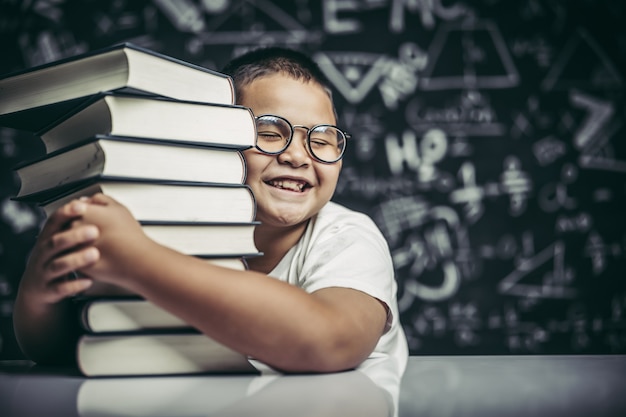 Um menino abraçando uma pilha de livros.