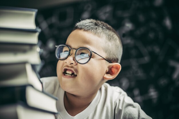 Um menino de óculos sentado na sala de aula contando livros