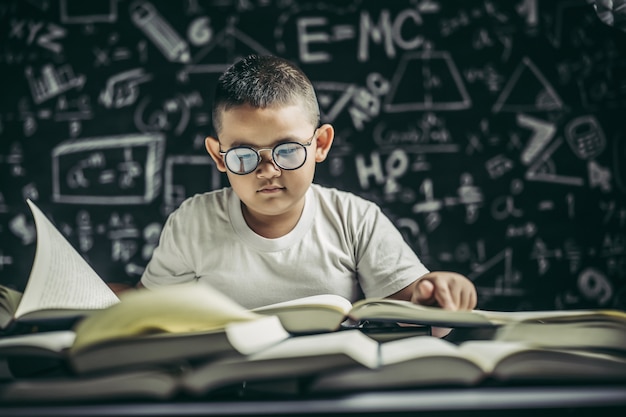 Um menino de óculos sentado na sala de aula lendo