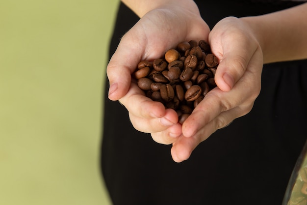 Um menino de vista frontal segurando sementes de café fresco