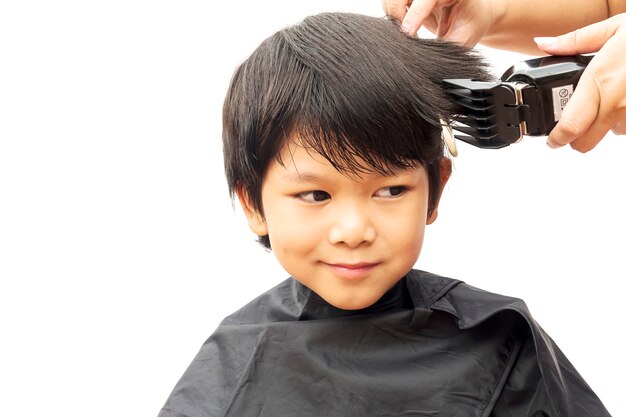 Um menino é cortado o cabelo por cabeleireiro isolado sobre o fundo branco