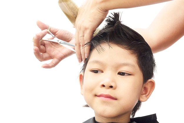 Um menino é cortado o cabelo por cabeleireiro isolado sobre o fundo branco
