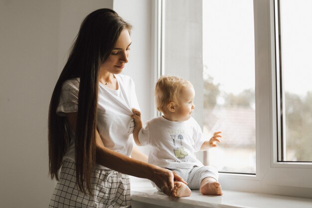 Um menino olha pela janela e sua mãe o admira