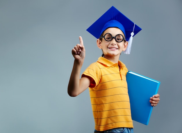 Um menino orgulhoso com óculos e boné de formatura.