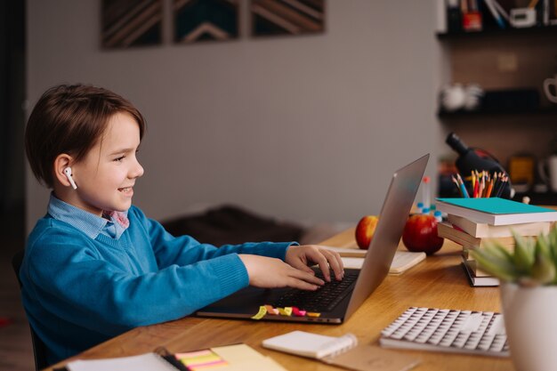Um menino pré-adolescente usa um laptop para fazer aulas online