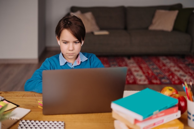 Um menino pré-adolescente usa um laptop para fazer aulas online