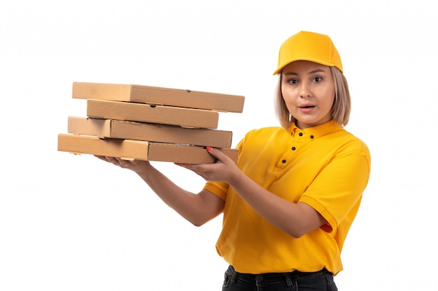 Um mensageiro feminino vista frontal na camisa amarela boné amarelo segurando caixas de pizza em branco