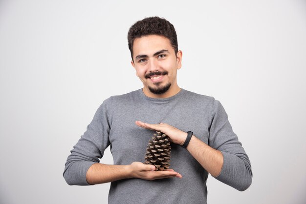 Um modelo de homem sorridente segurando uma pinha.