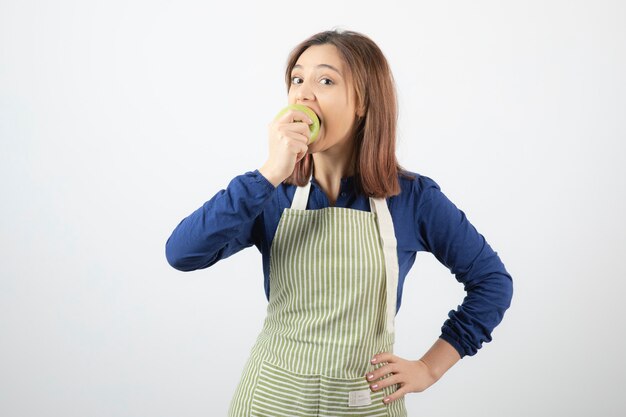 um modelo de jovem bonito no avental, comendo uma maçã verde fresca.