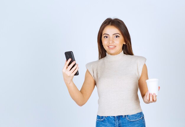 Um modelo de jovem sorridente segurando um telefone e olhando para a câmera.