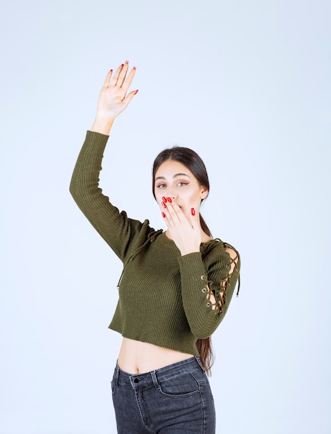 Um modelo de mulher jovem e bonita levantando a mão e cobrindo a boca.