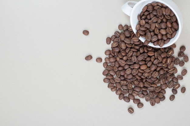 Um monte de grãos de café em uma caneca branca