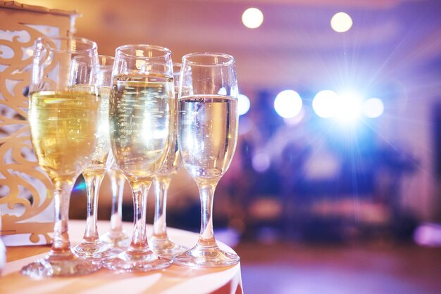 Um monte de taças de vinho em luz azul com um delicioso champanhe fresco ou vinho branco no bar.