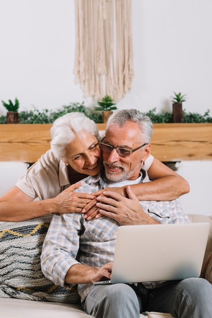 Um, mulher idosa, abraçar, dela, marido, usando computador portátil