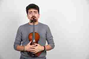 Foto grátis um músico segurando seu violino de madeira marrom e parece estressado.