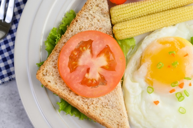 Foto grátis um ovo frito que coloca em uma torrada, coberto com sementes de pimenta com cenoura, milho de bebê e cebolinha.