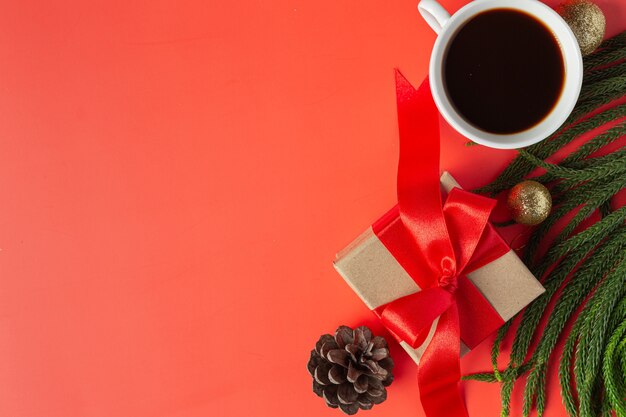 Um papel branco em branco, uma xícara de café e uma caixa de presente no chão vermelho