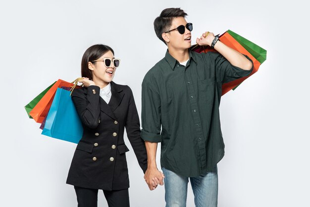 Um par de homens e mulheres usando óculos e carregando muitos sacos de papel para fazer compras