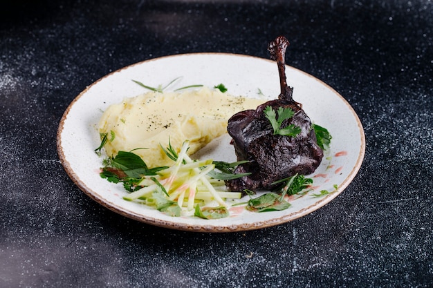 Um pedaço de bife com purê de batatas e ervas verdes.