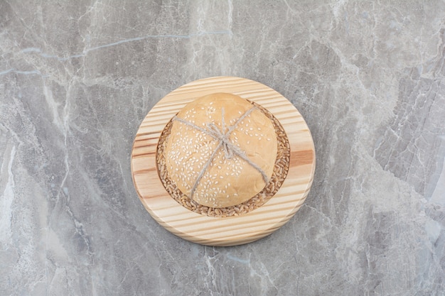Um pedaço de pão branco com grãos de aveia na placa de madeira