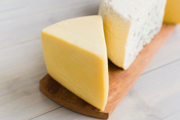 Um pedaço de queijo na tábua sobre a mesa de madeira