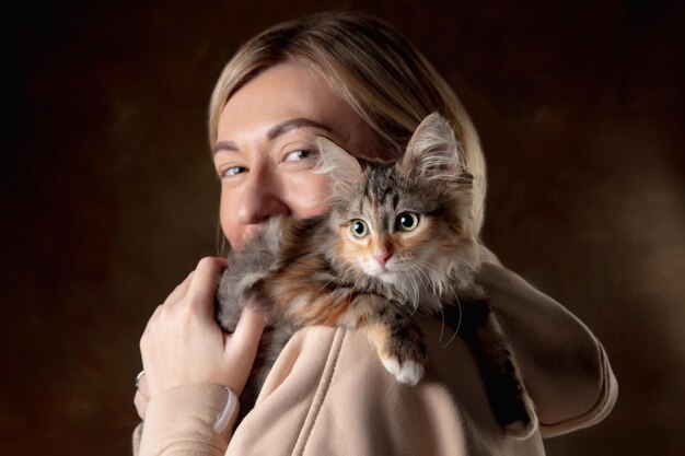 Um pequeno gatinho de raça pura sentado no ombro de uma jovem