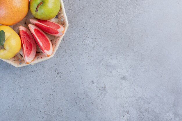 Um pequeno pacote de frutas em uma cesta branca sobre fundo de mármore.