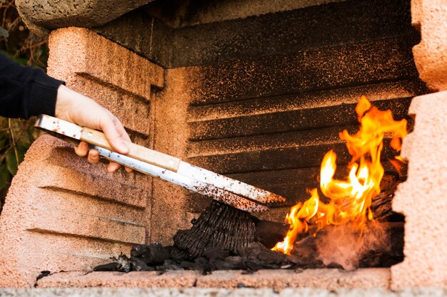 Um, pessoa, mão, queimadura, carvão, com, tong, em, firepit