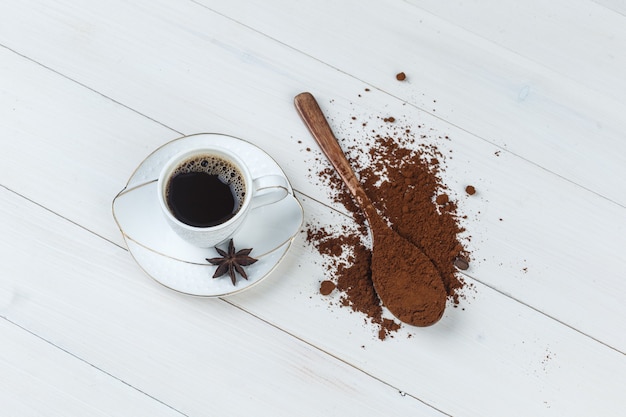 Um pouco de café com café moído, especiarias em uma xícara com fundo de madeira, plana leigos.