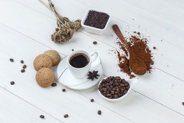 Um pouco de café com café moído, grãos de café, ervas secas, biscoitos