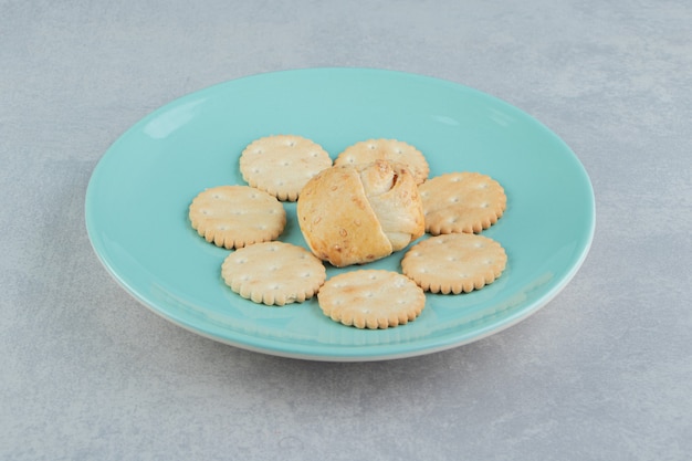 Um prato azul cheio de biscoitos doces crocantes com bolinho.