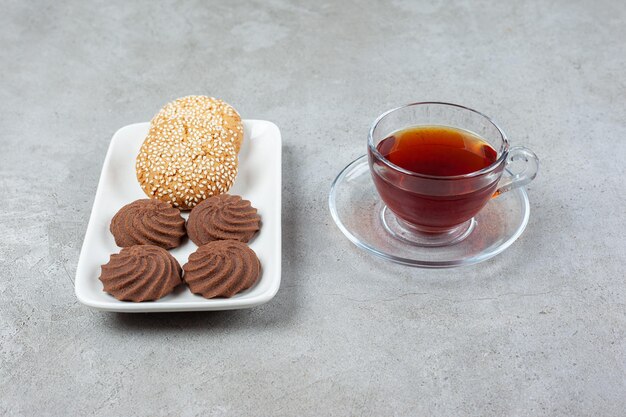 Um prato de biscoitos diferentes e uma xícara de chá perfumado na superfície de mármore