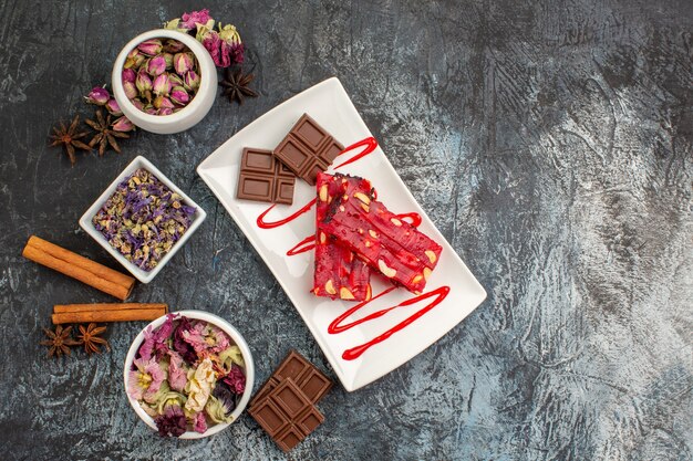 Um prato de chocolate e tigelas de flores secas ao redor em cinza