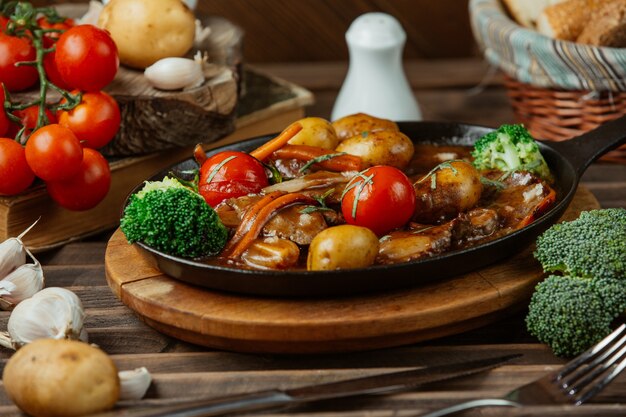 Um prato de cobre preto de alimentos grelhados e legumes.