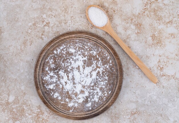 Um prato de farinha marrom e uma colher de pau de açúcar