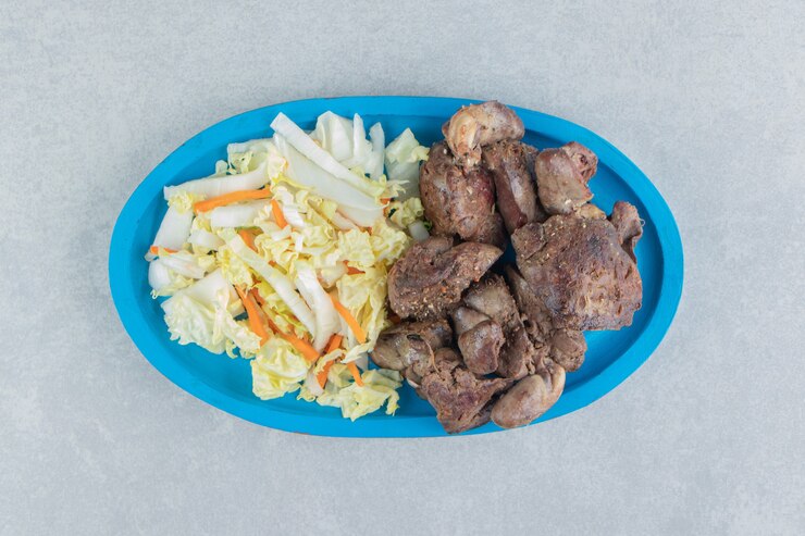 Foto grátis um prato de madeira azul com carne frita e salada de legumes.